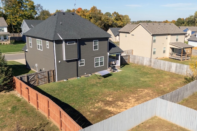 back of house with a residential view, a fenced backyard, and a lawn