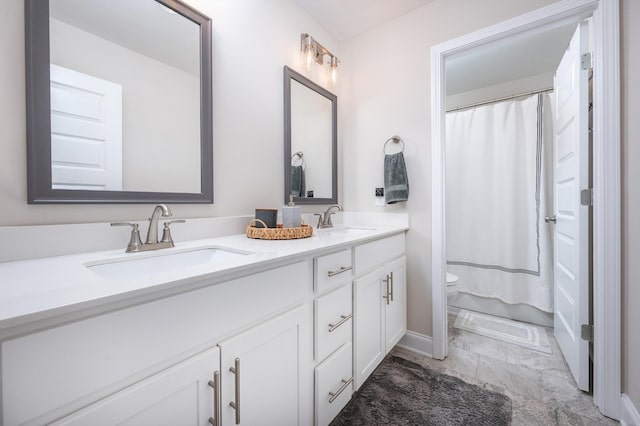 full bathroom with marble finish floor, a sink, toilet, and double vanity