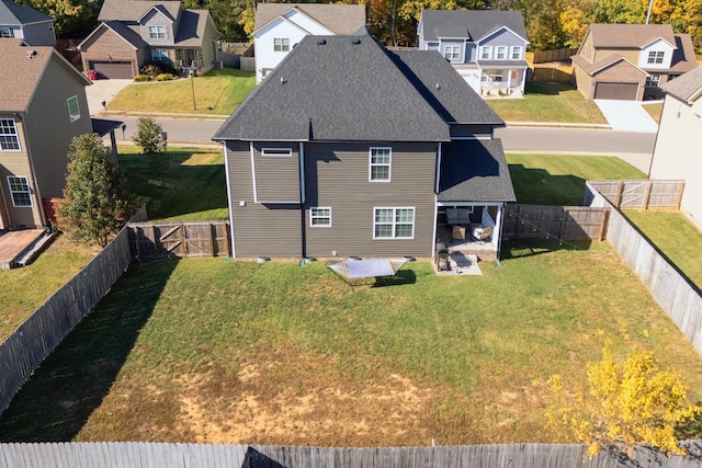 back of property featuring roof with shingles, a yard, a patio, a residential view, and a fenced backyard