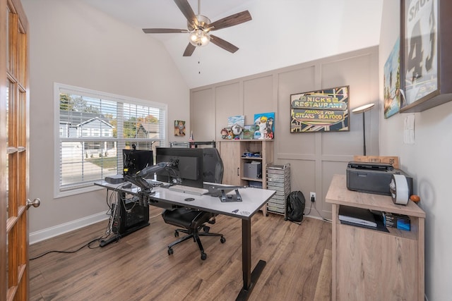 office space featuring ceiling fan, high vaulted ceiling, a decorative wall, wood finished floors, and baseboards