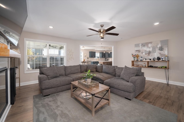 living room featuring baseboards, a glass covered fireplace, wood finished floors, and recessed lighting