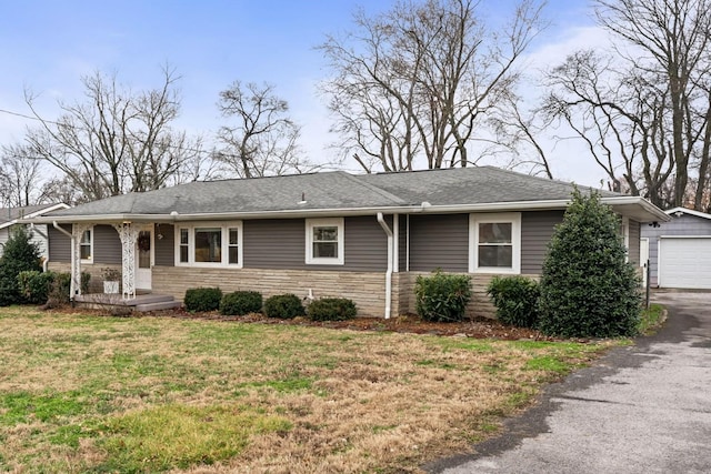 single story home with stone siding, roof with shingles, a detached garage, and a front yard