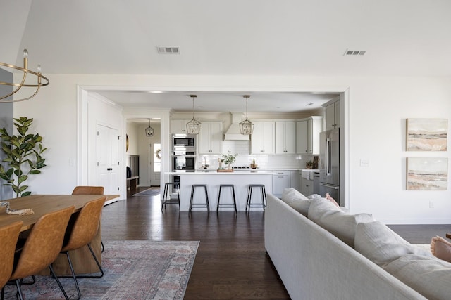 living room featuring dark wood-style floors, visible vents, and crown molding