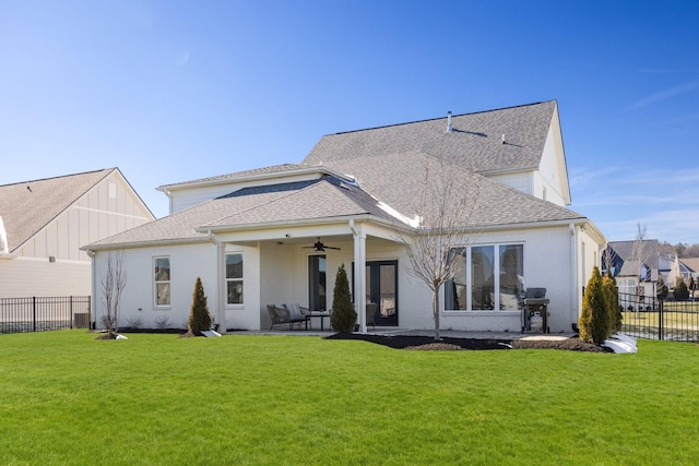 rear view of house with ceiling fan, fence, and a lawn