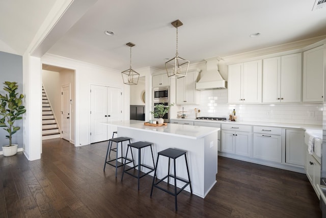 kitchen with stainless steel appliances, tasteful backsplash, custom exhaust hood, and a kitchen breakfast bar