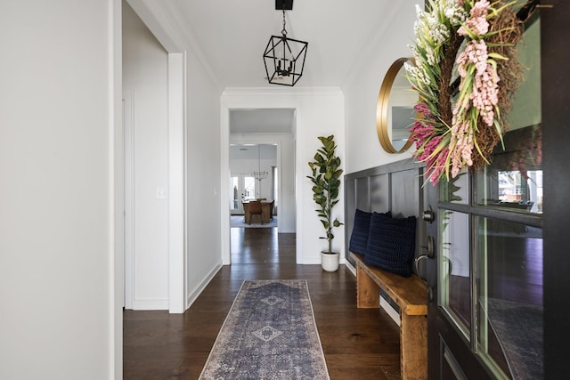 hall featuring a chandelier, dark wood-style flooring, ornamental molding, and baseboards