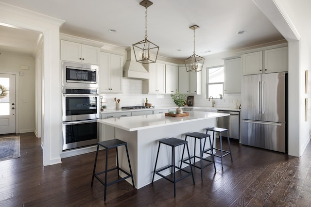 kitchen with appliances with stainless steel finishes, a center island, a breakfast bar, and custom range hood