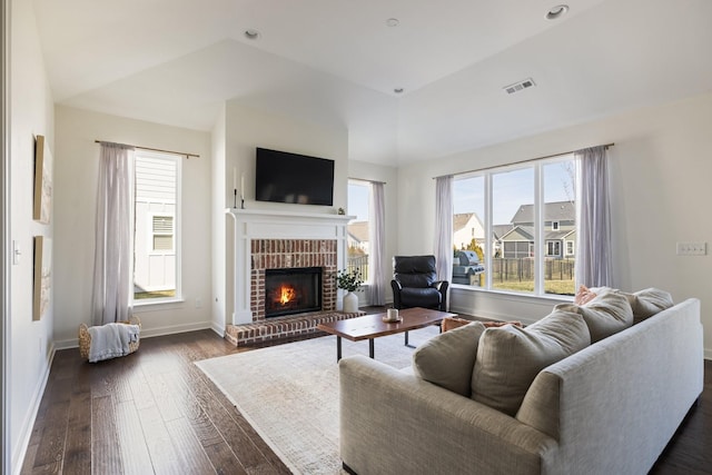 living room with dark wood-style floors, visible vents, plenty of natural light, and a fireplace