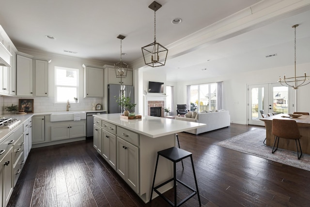 kitchen featuring dark wood finished floors, open floor plan, appliances with stainless steel finishes, decorative backsplash, and a kitchen bar