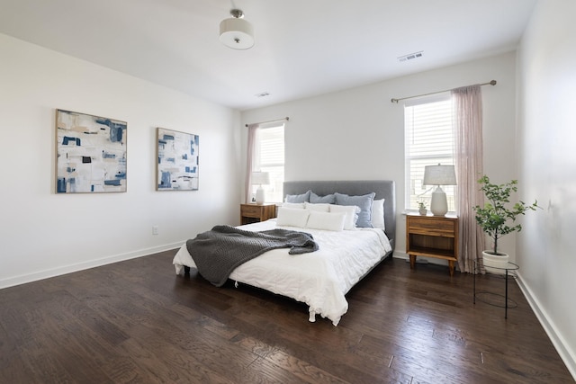 bedroom featuring baseboards, multiple windows, visible vents, and dark wood finished floors