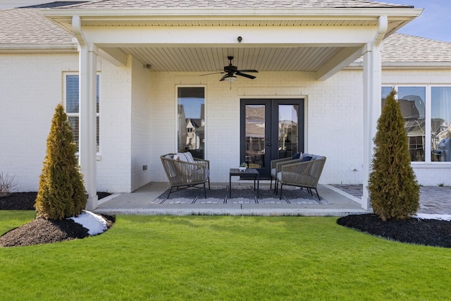 property entrance with a shingled roof, ceiling fan, a yard, a patio area, and brick siding