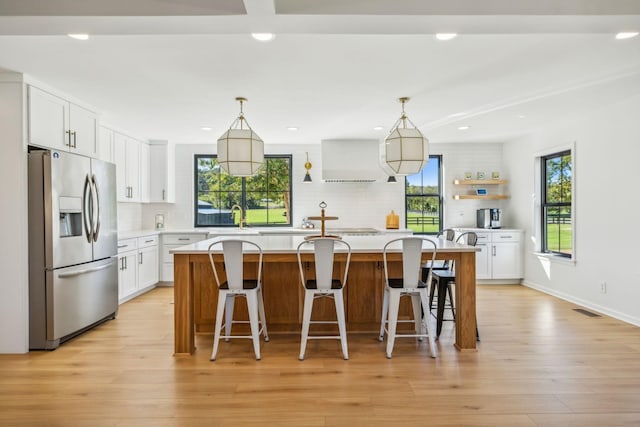 kitchen featuring white cabinetry, stainless steel fridge with ice dispenser, light countertops, a center island, and open shelves