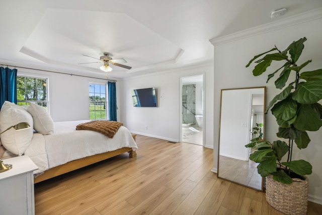 bedroom with ornamental molding, light wood-type flooring, a raised ceiling, and baseboards