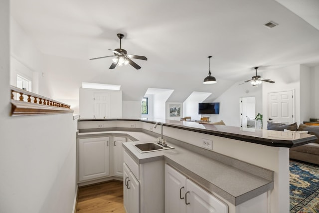 kitchen with a sink, visible vents, white cabinets, open floor plan, and vaulted ceiling