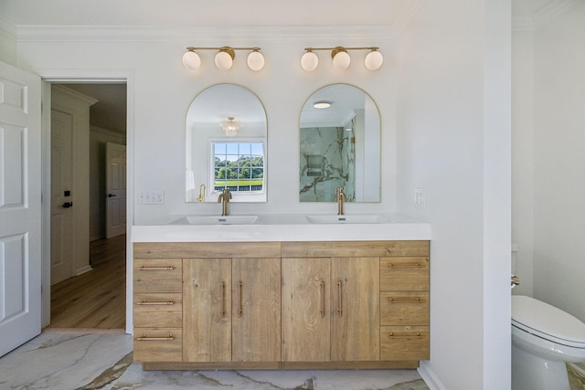 full bathroom featuring double vanity, ornamental molding, a sink, and toilet