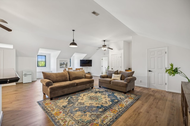 living room with a ceiling fan, vaulted ceiling, baseboards, and wood finished floors