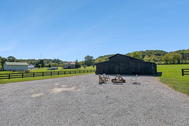 view of yard with a detached garage, fence, an outdoor structure, and a rural view