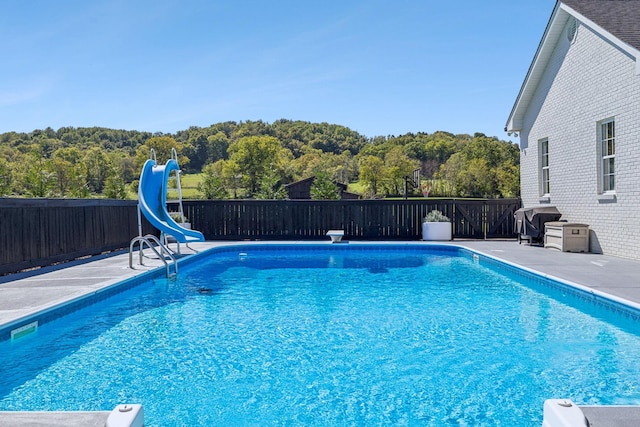 view of pool featuring a fenced in pool, a patio, area for grilling, fence, and a water slide