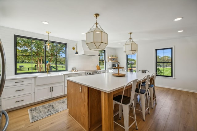 kitchen with premium range hood, hanging light fixtures, light countertops, a center island, and open shelves