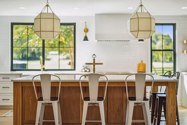 kitchen with light countertops, hanging light fixtures, brown cabinetry, and white cabinets