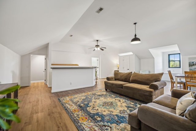 living room with light wood-style flooring, visible vents, vaulted ceiling, and a ceiling fan