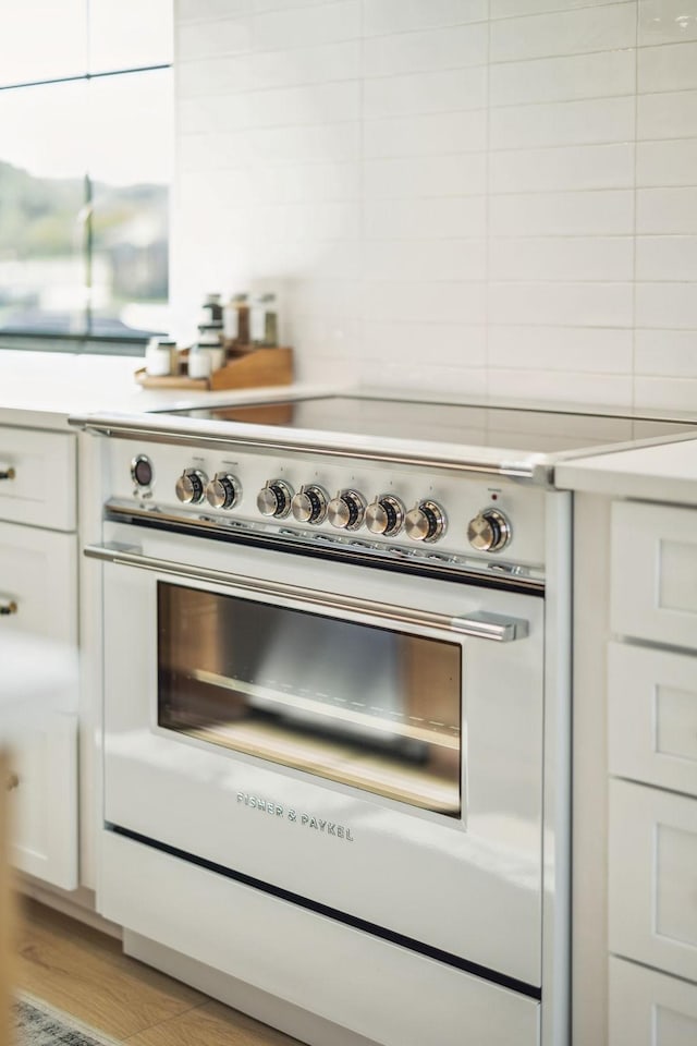 interior details featuring light countertops, high end stove, and white cabinetry