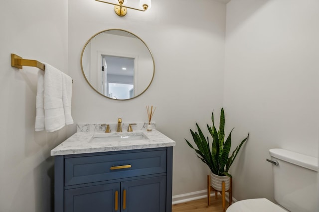 bathroom with toilet, baseboards, wood finished floors, and vanity