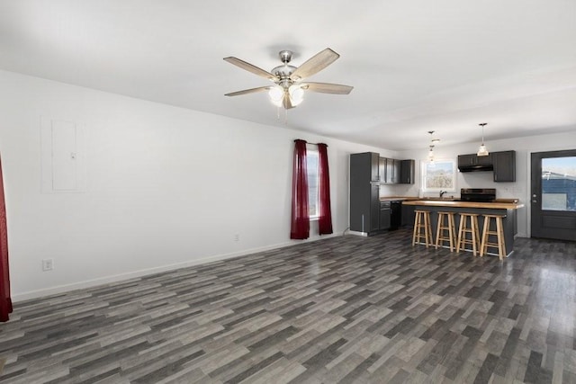 unfurnished living room with a ceiling fan, dark wood-type flooring, and baseboards