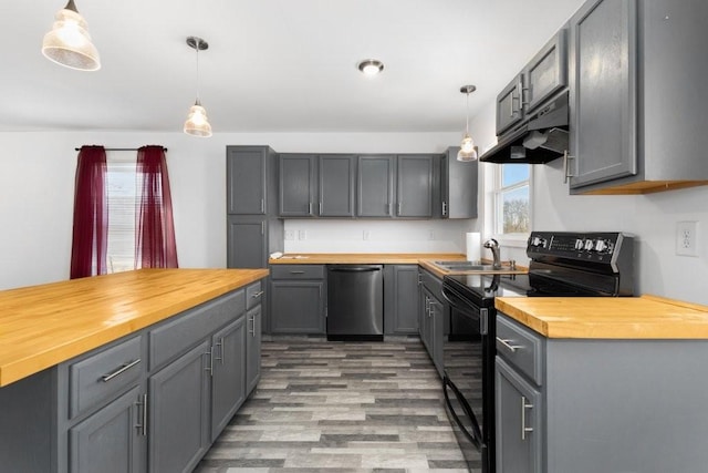 kitchen featuring under cabinet range hood, butcher block counters, a sink, gray cabinets, and black appliances