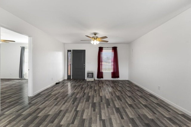 interior space featuring ceiling fan, dark wood-style flooring, baseboards, and heating unit