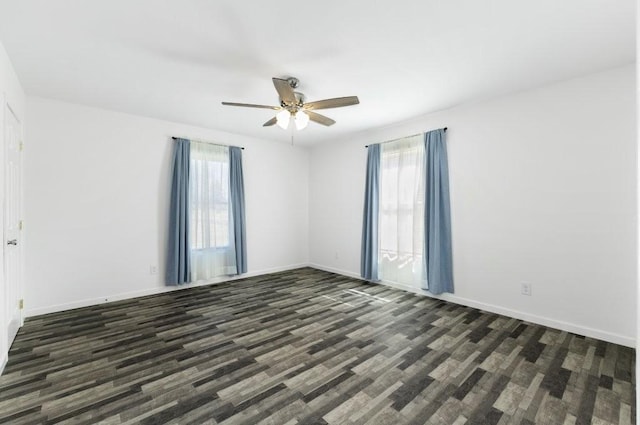 unfurnished room featuring dark wood finished floors, a ceiling fan, and baseboards