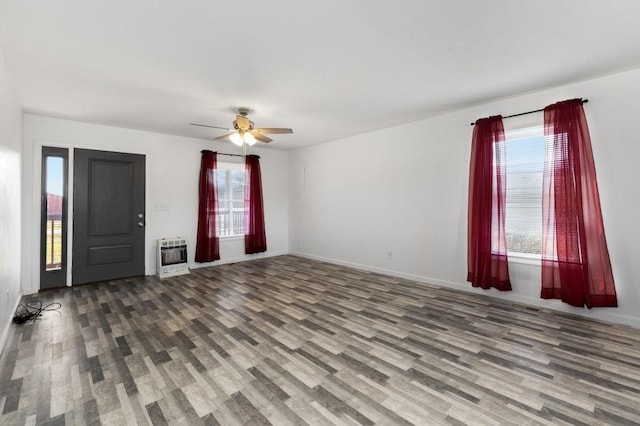 interior space featuring baseboards, ceiling fan, heating unit, and wood finished floors