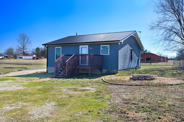 back of house with a fire pit, metal roof, a yard, and fence