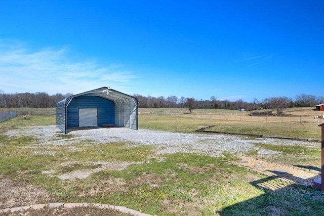 view of yard featuring driveway, a carport, a rural view, and a detached garage