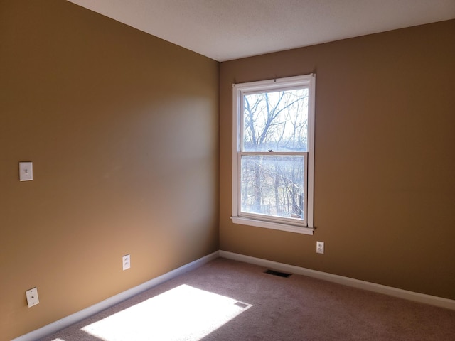 carpeted empty room featuring baseboards and visible vents