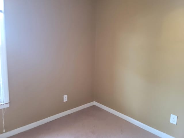 unfurnished room with carpet and baseboards