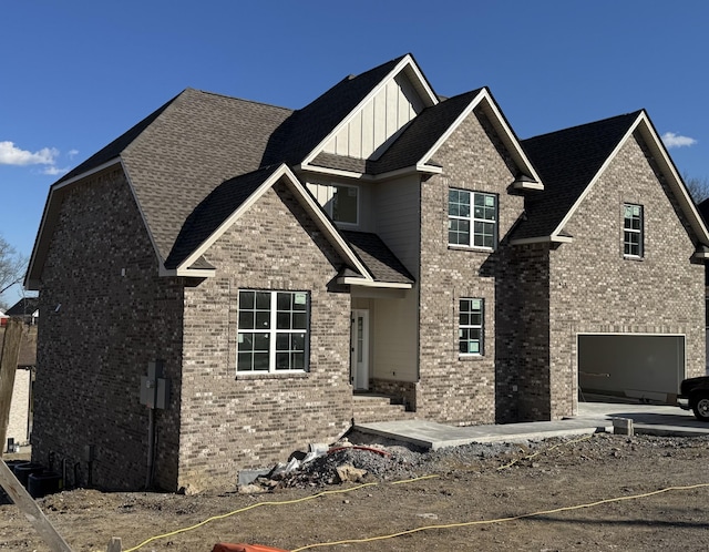 view of front of property featuring board and batten siding, brick siding, a shingled roof, and an attached garage