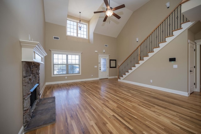 unfurnished living room featuring a fireplace, light wood finished floors, visible vents, baseboards, and stairs