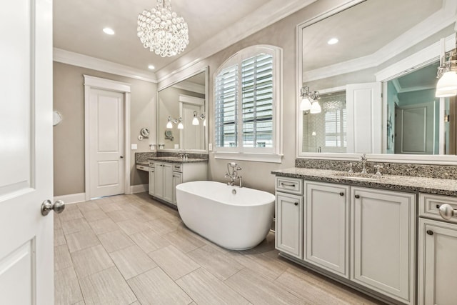 full bath with baseboards, a soaking tub, ornamental molding, two vanities, and a sink