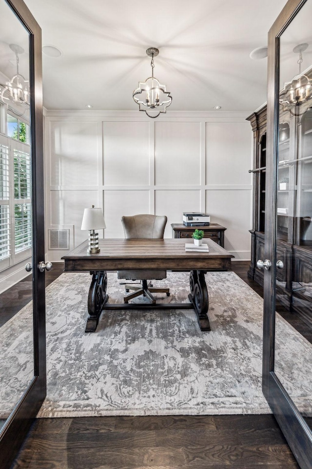 office with a notable chandelier, dark wood-type flooring, visible vents, and a decorative wall