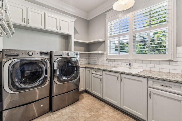 laundry room featuring ornamental molding, cabinet space, a sink, and washer and clothes dryer