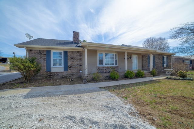 single story home with a front yard, a chimney, and brick siding