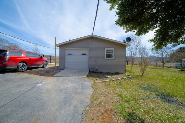 detached garage featuring driveway and fence