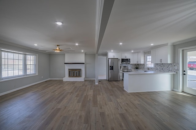 kitchen featuring white cabinetry, appliances with stainless steel finishes, open floor plan, and a sink