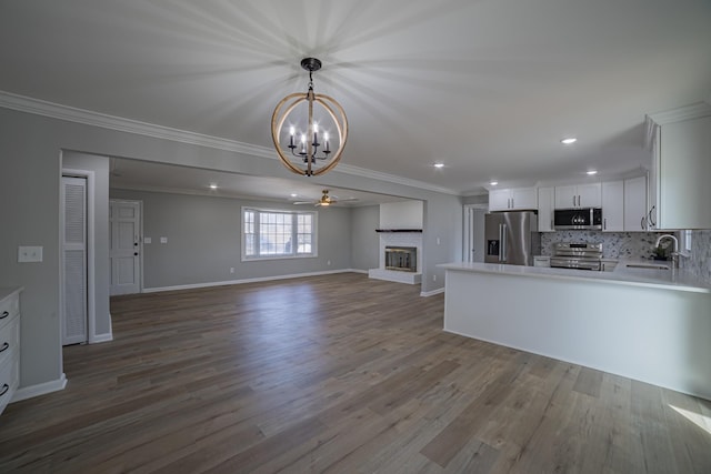 kitchen featuring a brick fireplace, ornamental molding, stainless steel appliances, and open floor plan