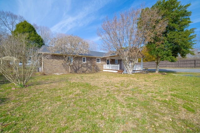 exterior space featuring brick siding, a front yard, and fence