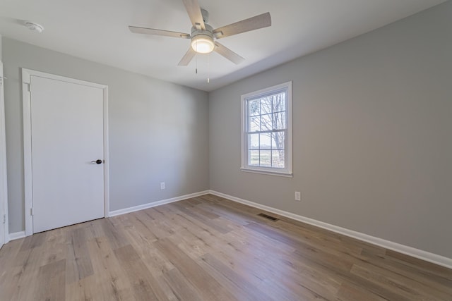 unfurnished room with a ceiling fan, baseboards, visible vents, and light wood finished floors