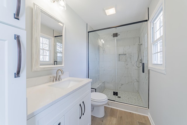 full bath featuring toilet, vanity, a marble finish shower, and wood finished floors