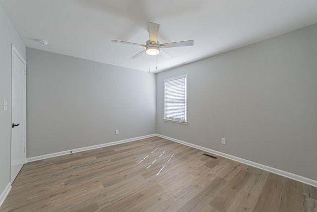 empty room featuring baseboards, ceiling fan, visible vents, and light wood-style floors