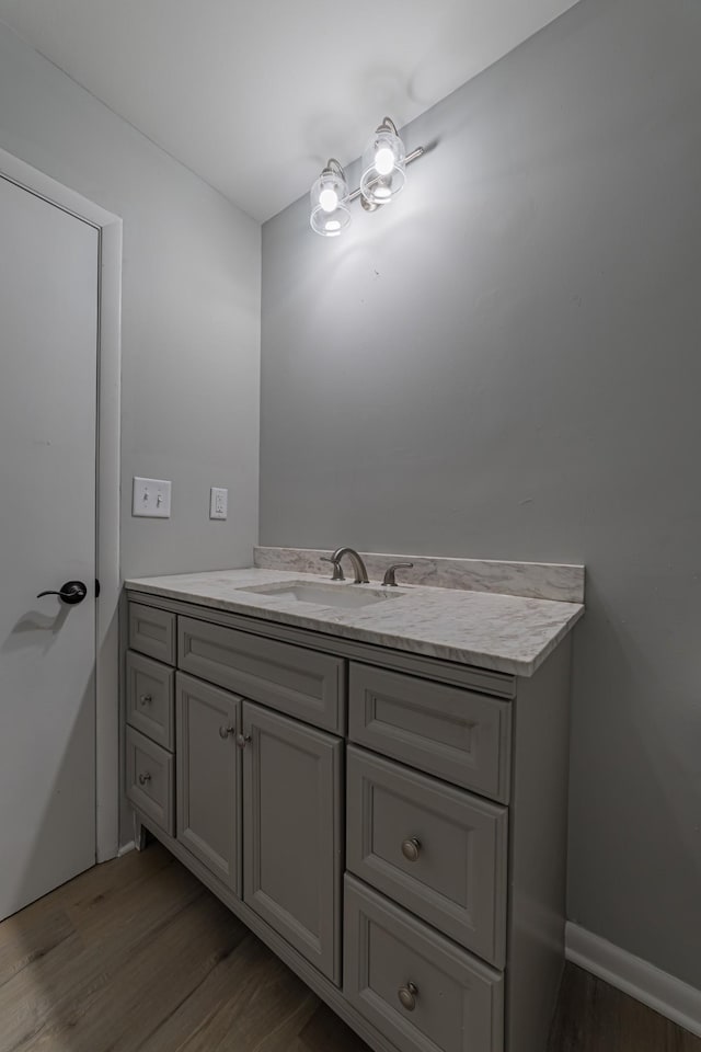 bathroom with a notable chandelier, baseboards, wood finished floors, and vanity